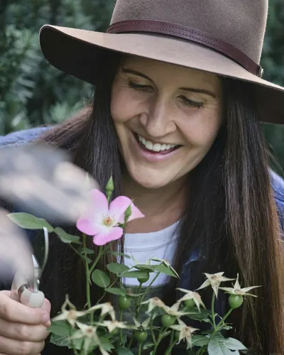 Gardener in a hat smiling among flowers