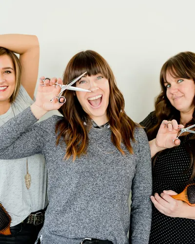 Three hair stylists laughing in their salon